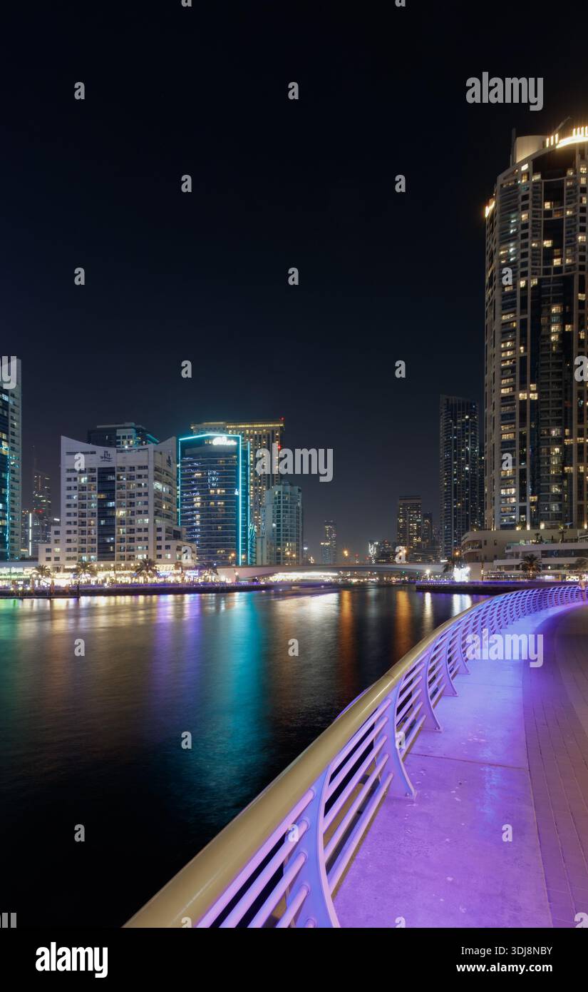 Dubai Marina, Vereinigte Arabische Emirate - 13. März 2025: Dubai Marina at Night verfügt über hohe Gebäude mit bunten Lichtern und einen geschwungenen Gang entlang der Stockfoto