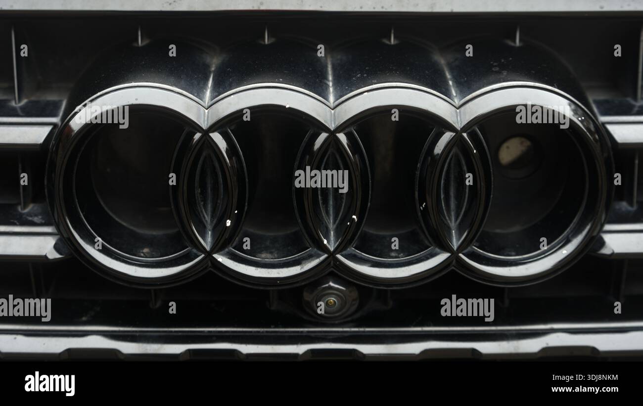 Nahaufnahme eines glänzenden Audi Emblems mit vier Chromringen auf schwarzem Hintergrund, die Präzision und modernes Automobildesign hervorheben. Stockfoto