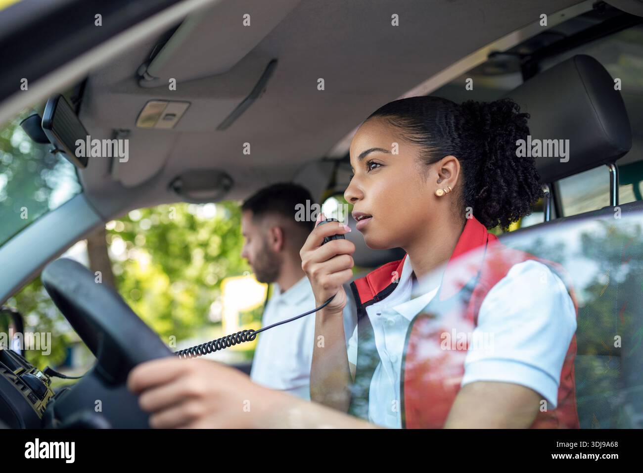 Zwei Sanitäter im Krankenwagen. afroamerikanische Rettungssanitäterin fährt und spricht über das Radio Stockfoto