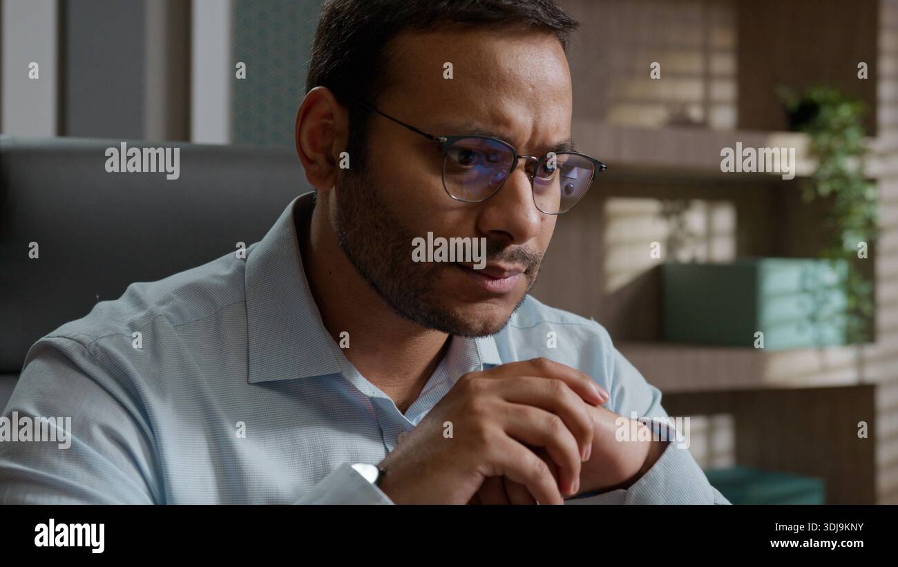 Ernsthaft fokussierter indischer arabischer Geschäftsmann in Brille, der Nachrichten auf Laptop im Büro liest, besorgte Arbeitgeber Programmierer Arbeit am Arbeitsplatz konzentriert Stockfoto