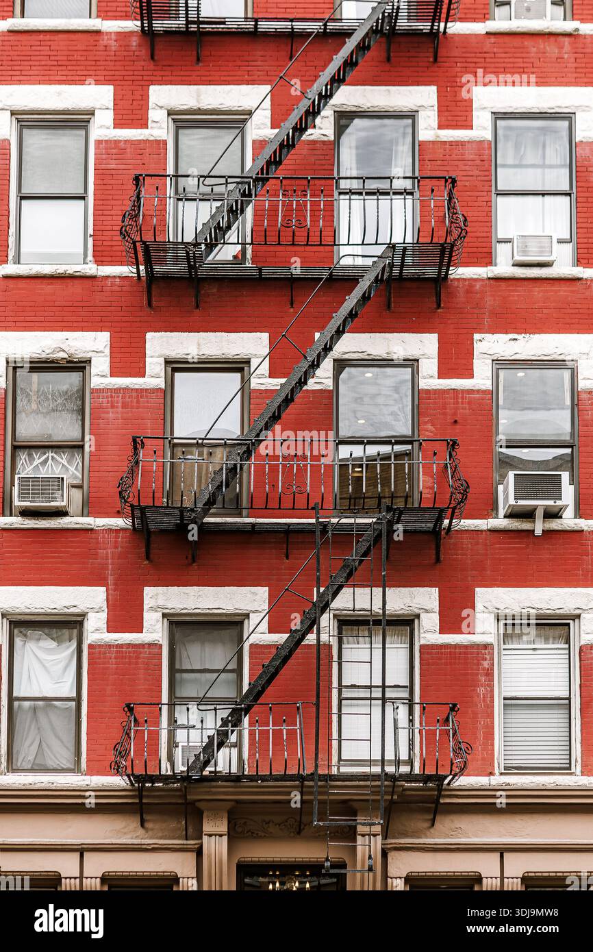New Yorker Apartmentfassade aus rotem Backstein mit klassischen Kaminflüchten, symmetrischen Fenstern und urbanen architektonischen Details. Kultiges Außendesign der Stadt, das Autom einfängt Stockfoto