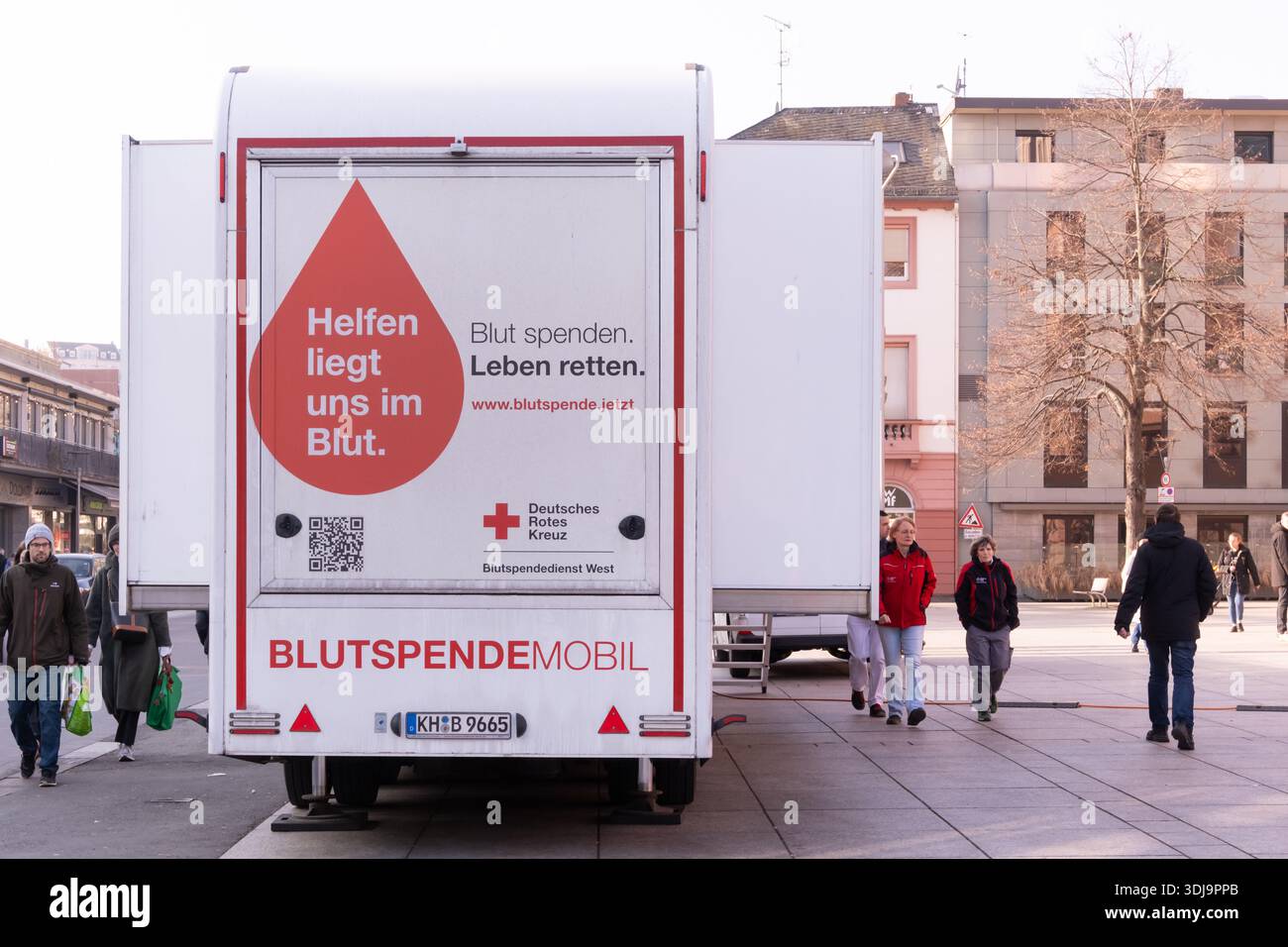 Mainz - 24. Januar 2026: Menschen laufen in der Nähe des Blutspendefahrzeugs in Mainz für Spenden. Stockfoto
