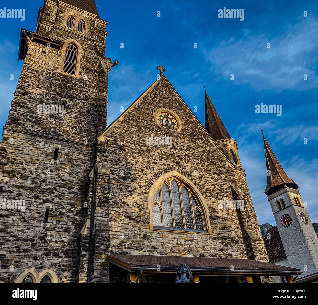 Ein dramatischer Blick auf die historische Schlosskirche in Interlaken, Schweiz, mit den komplizierten Mauerwerken und Glockentürmen - Smartphone-aufgenommenes Stockfoto