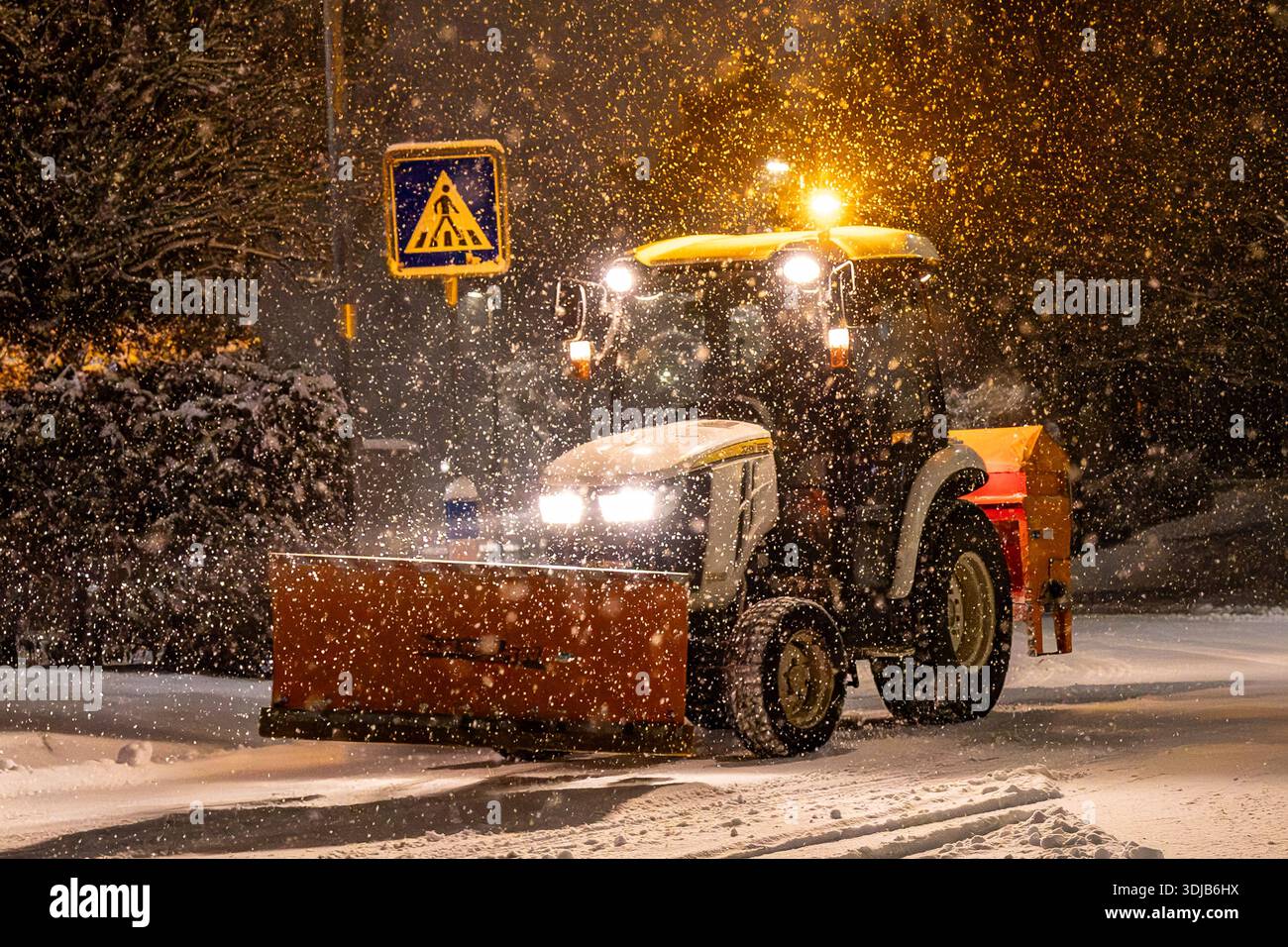 Kompakttraktor mit Schneeräumschild, der bei Wintereinsätzen am frühen Morgen in Bad Homburg Schnee von einer Wohnstraße entfernt. Stockfoto