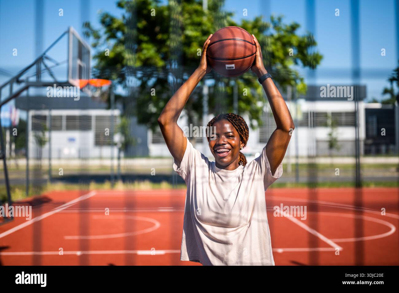 Afroamerikanische Spielerin hält einen Ball und lacht während des Sommertrainings. Aktiver Lifestyle und Stadtsport. Stockfoto