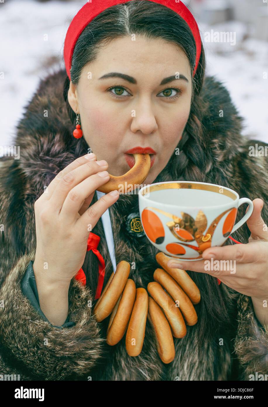 Eine Frau im Pelzmantel isst Kalach mit Tee Stockfoto