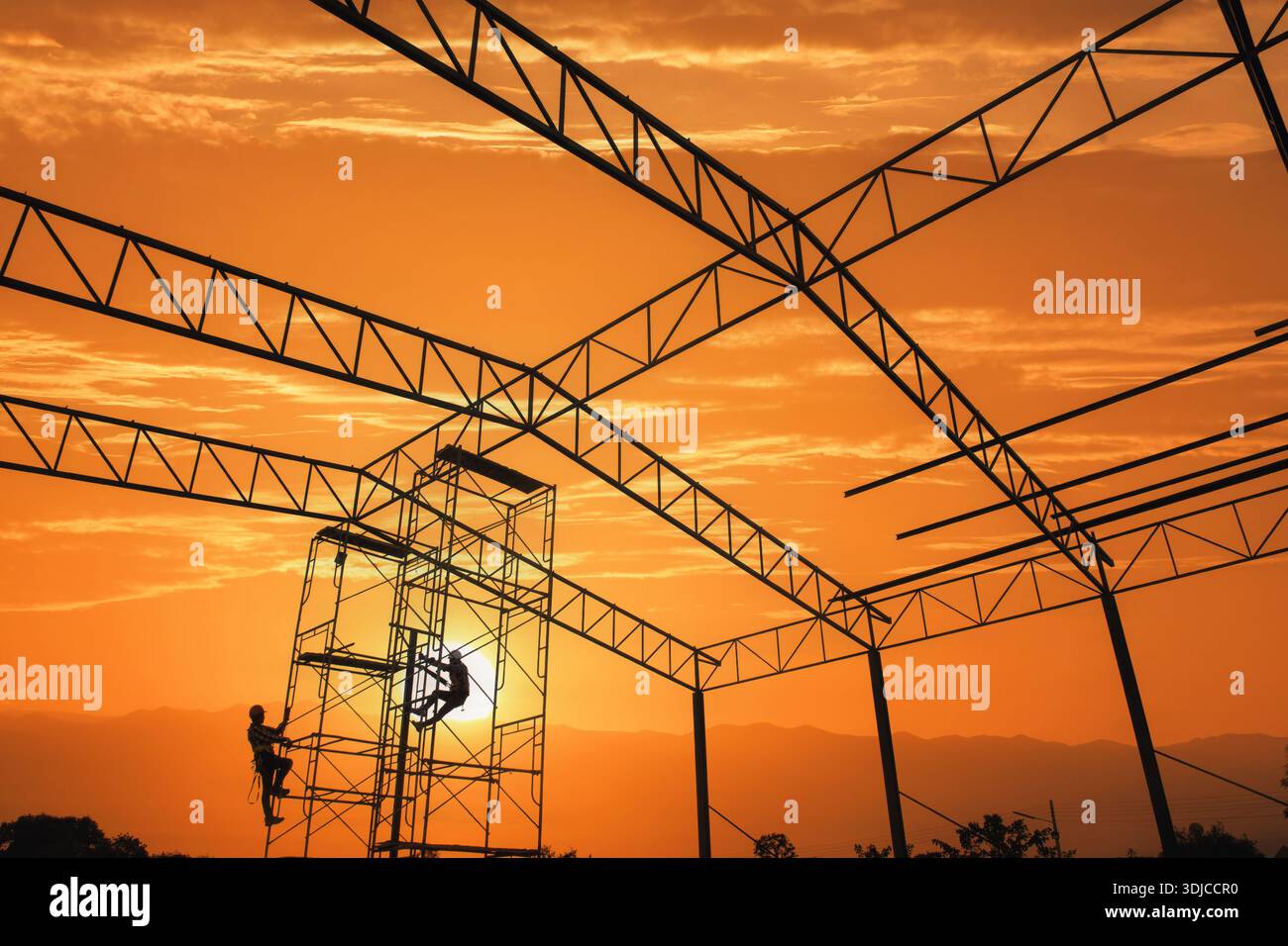 Silhouette von zwei Bauarbeitern, die bei Sonnenuntergang auf Stahlkonstruktionen klettern, Thailand Stockfoto