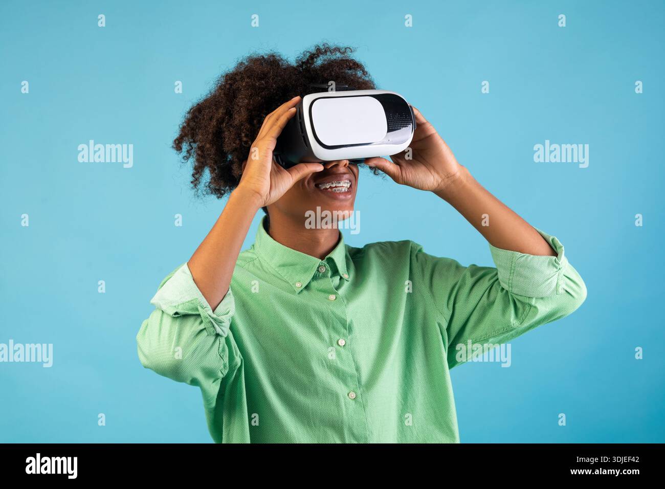 Erleben Sie futuristische Technologien. Schwarzer Kerl trägt und berührt VR-Headset, erkunden Cyberspace, blauer Hintergrund Stockfoto