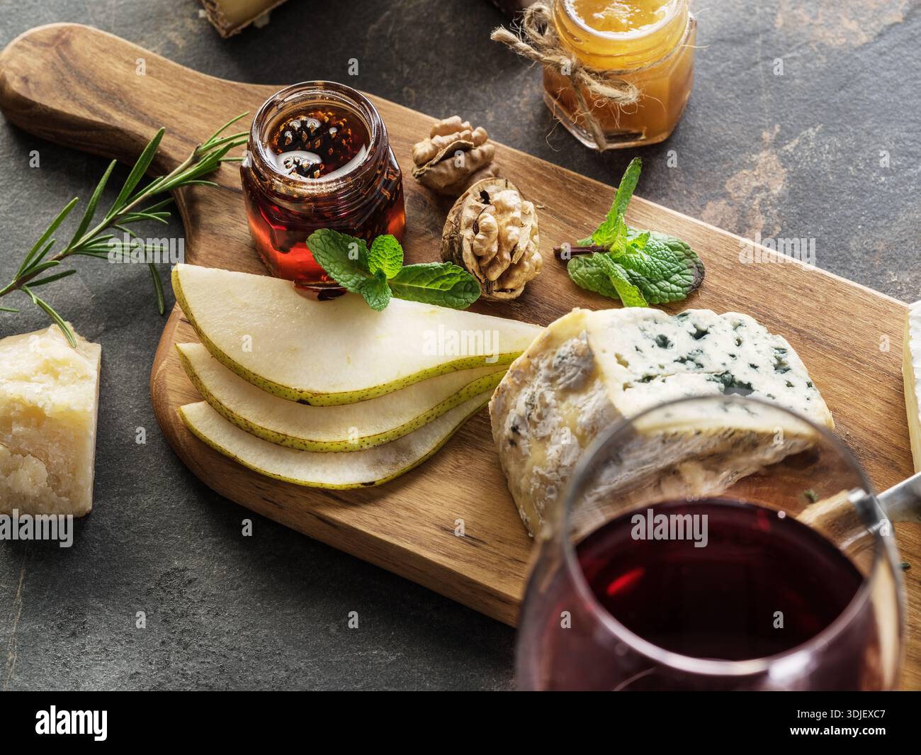 Verschiedene Käseplatten auf rustikalem Holzbrett mit einem Glas Rotwein. Verschiedene Hart- und Weichkäse für Weinproben. Restaurant-Menü-Konzept. Stockfoto