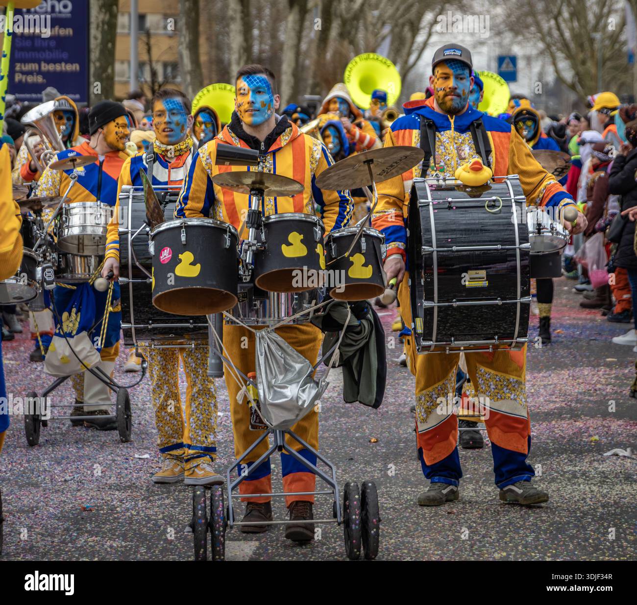 Zug, Schweiz - 1. März 2025: Guggenmusik marschierende Blaskapelle in bunten Kostümen und Gesichtsfarbe tritt bei der Fasnacht-Winterkarnevalsparade auf Stockfoto