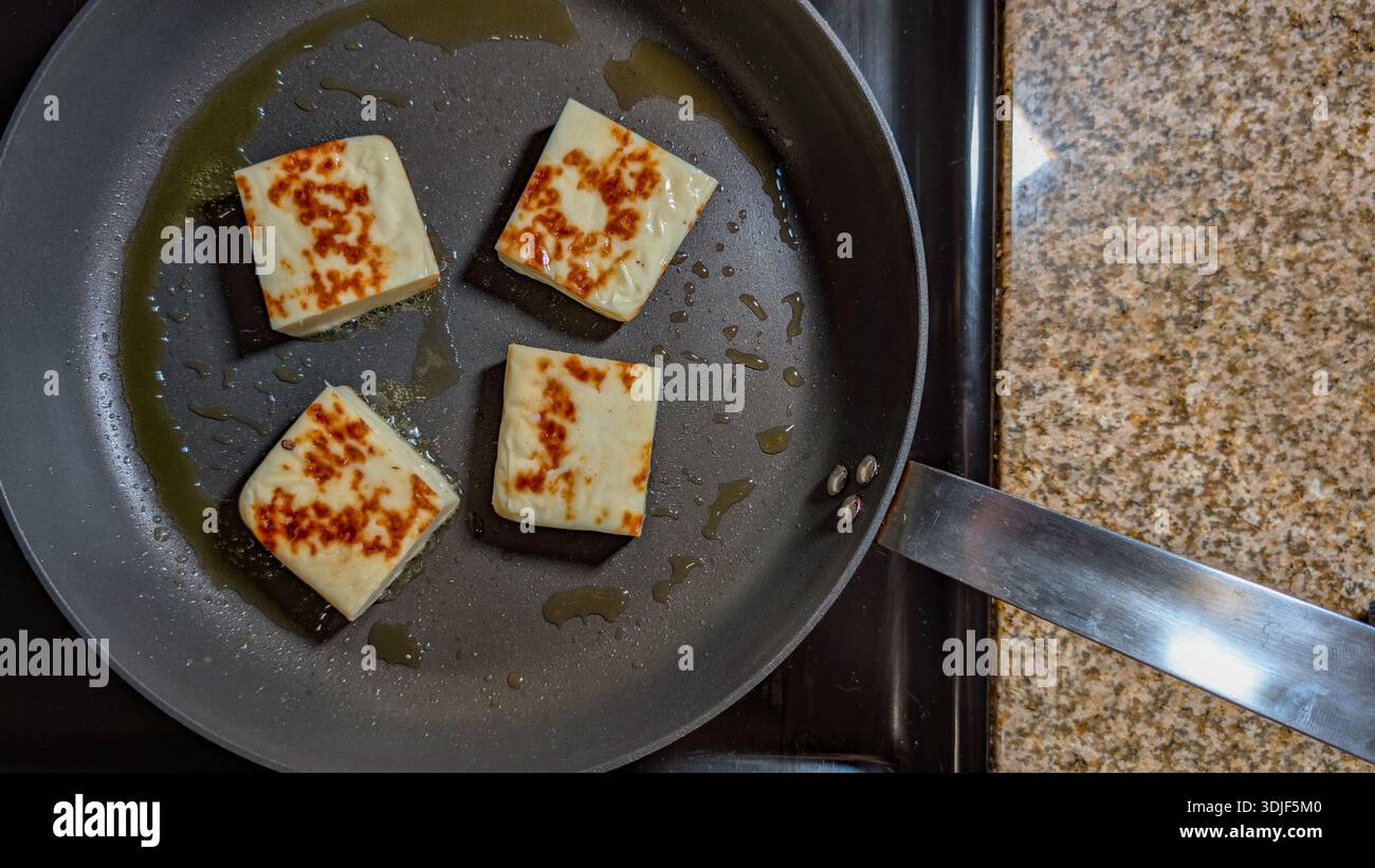 Blick von oben nach unten auf den halloumi-Käse, der in einer Pfanne brutzelt Stockfoto