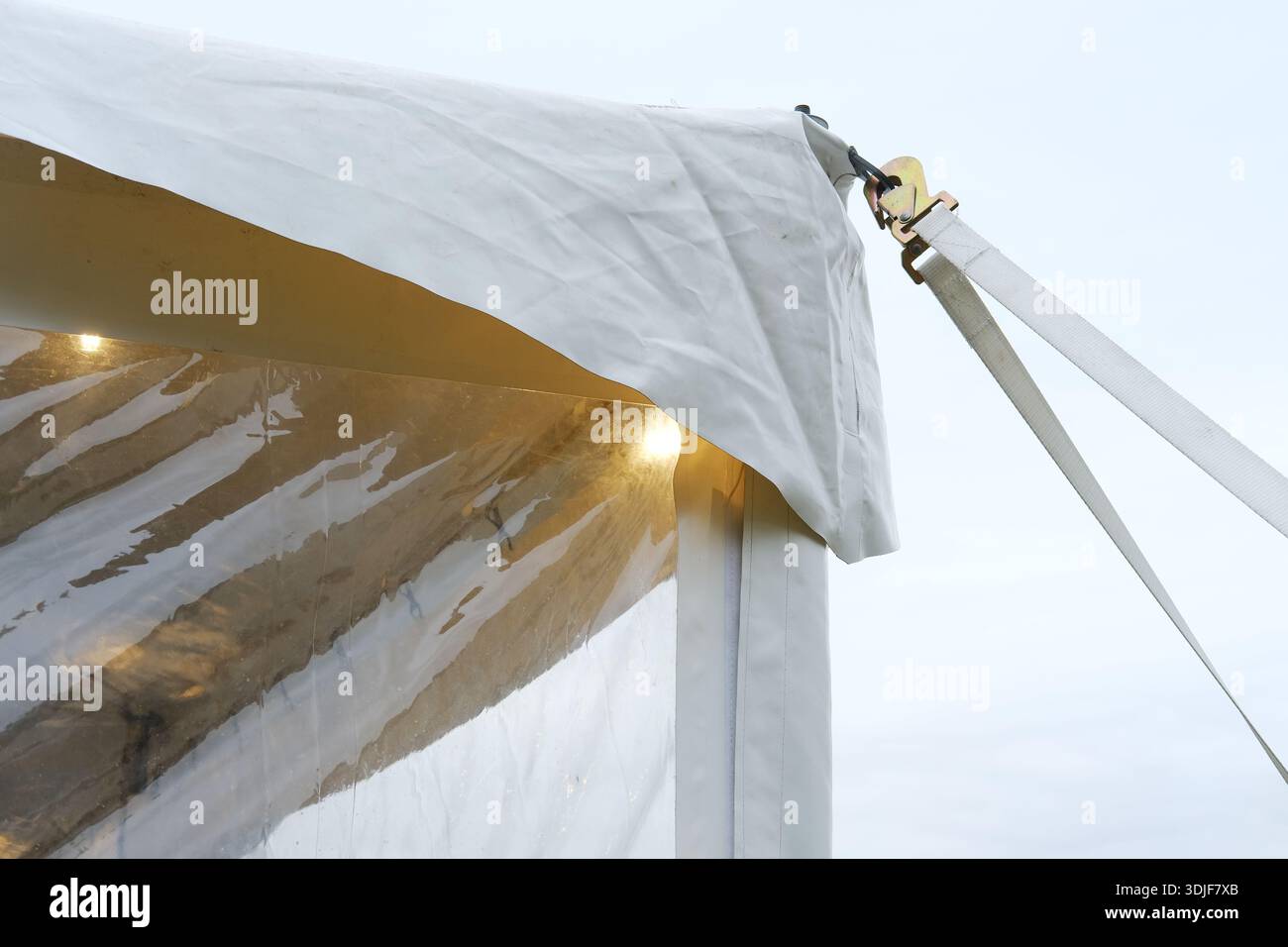 Sichern Sie ein Zelt mit Gurten und Clips, um Stabilität gegen Wind zu gewährleisten, und betonen Sie strapazierfähige Materialien und Outdoor-Setup für Veranstaltungen und Zusammenkünfte Stockfoto