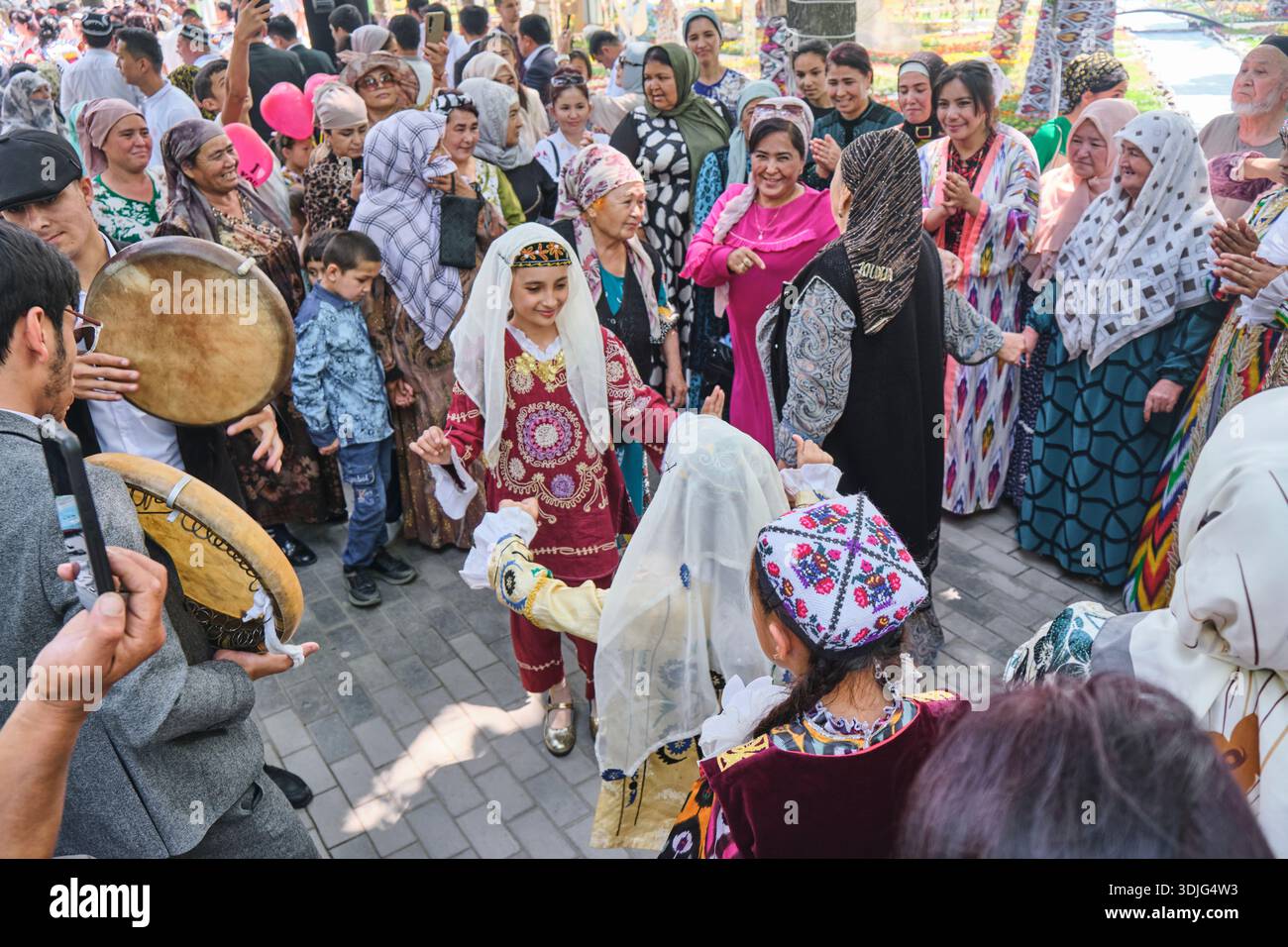 Familien in traditioneller Kleidung, Tanz und Feiern. Beim jährlichen Frühlingsblumenfest im Babur Park. In Namangan, Fergana Valley, Usbekistan. Stockfoto
