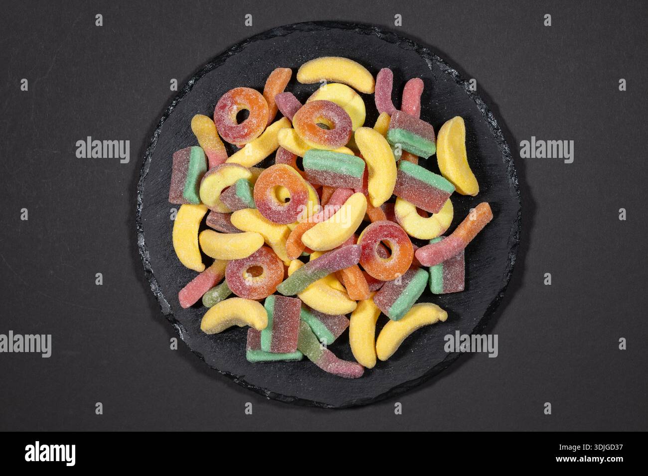 Haufen Sie Gelee Bonbons auf Steinplatte, auf dunklem Hintergrund. Stockfoto