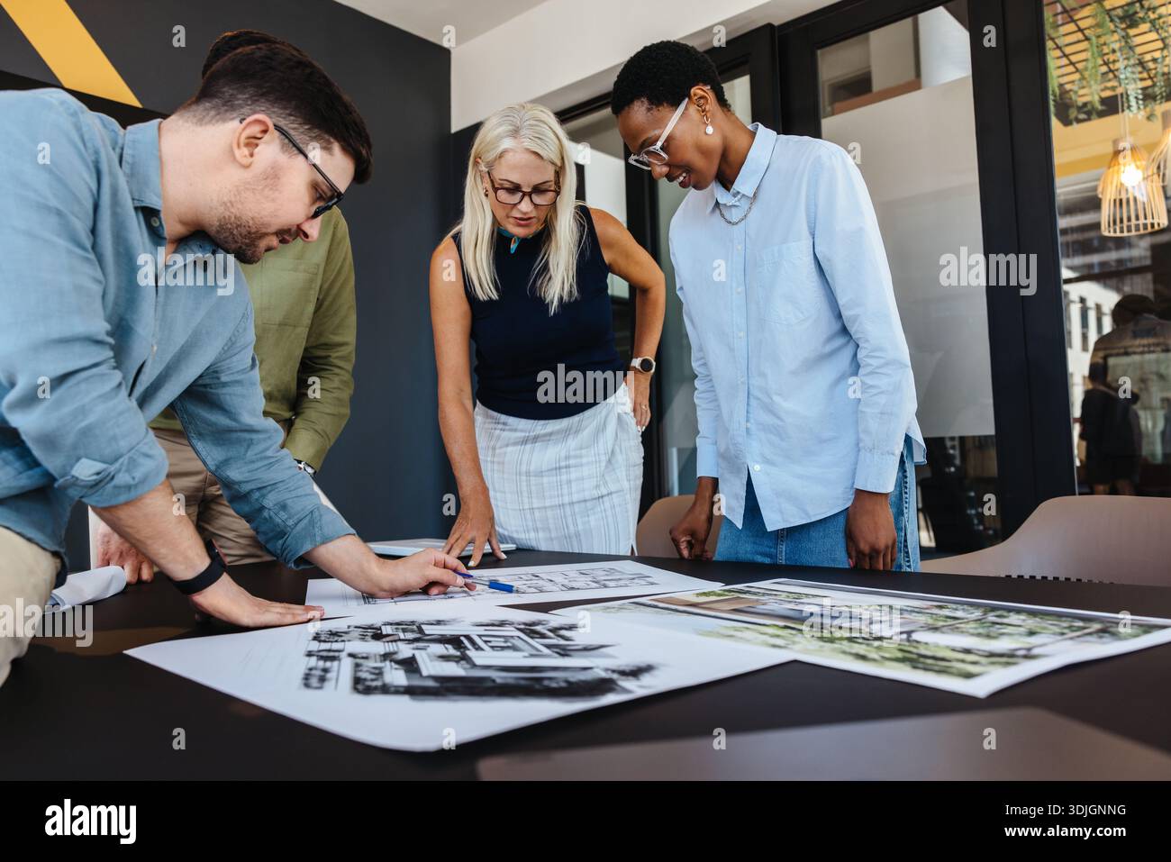 Gruppe multiethnischer Erwachsener, die in einer Büroumgebung an architektonischen Plänen arbeiten und Teamarbeit zeigen Stockfoto