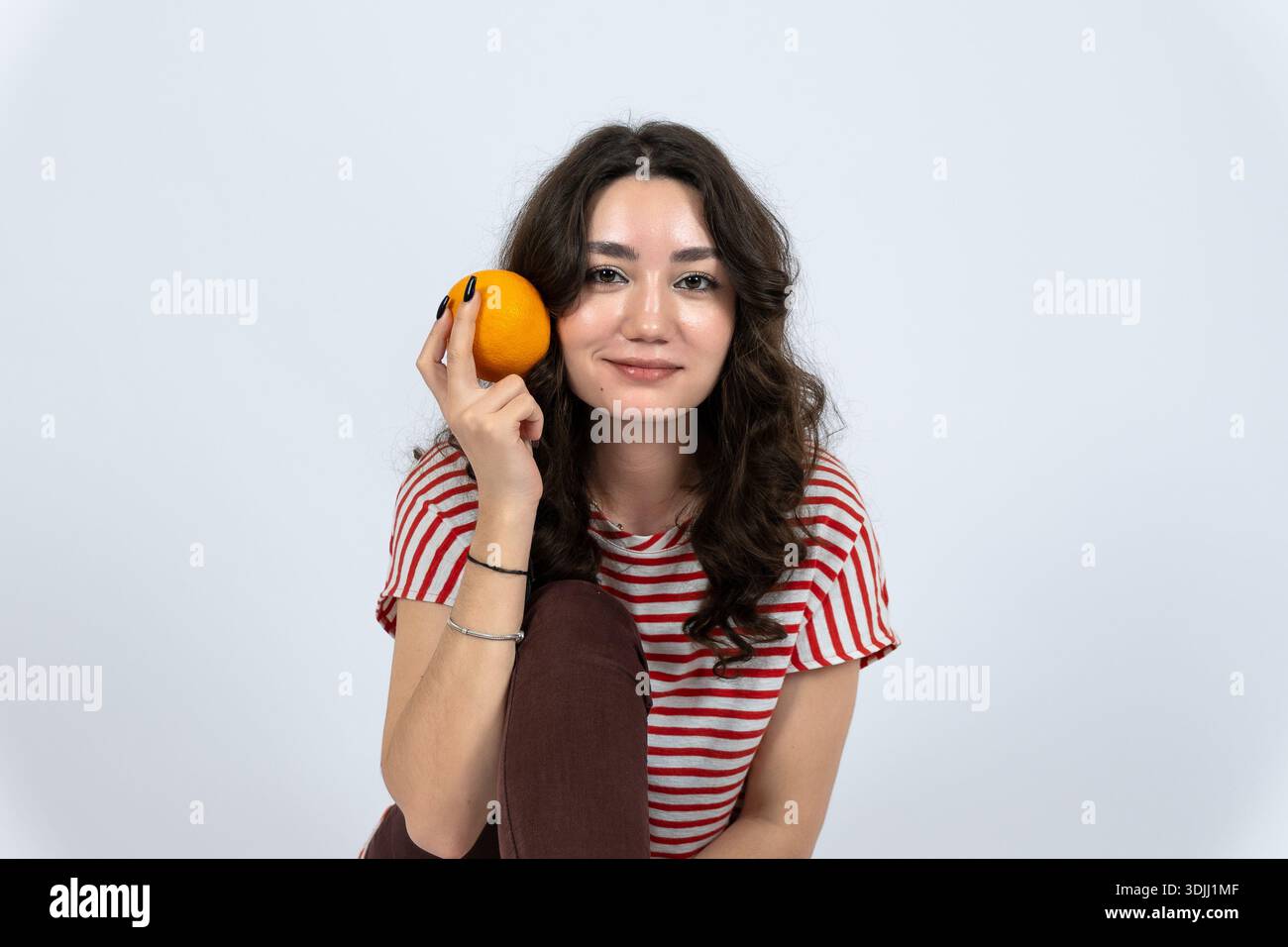Junge Frau, die eine Orange für gesunde Ernährung hält Stockfoto