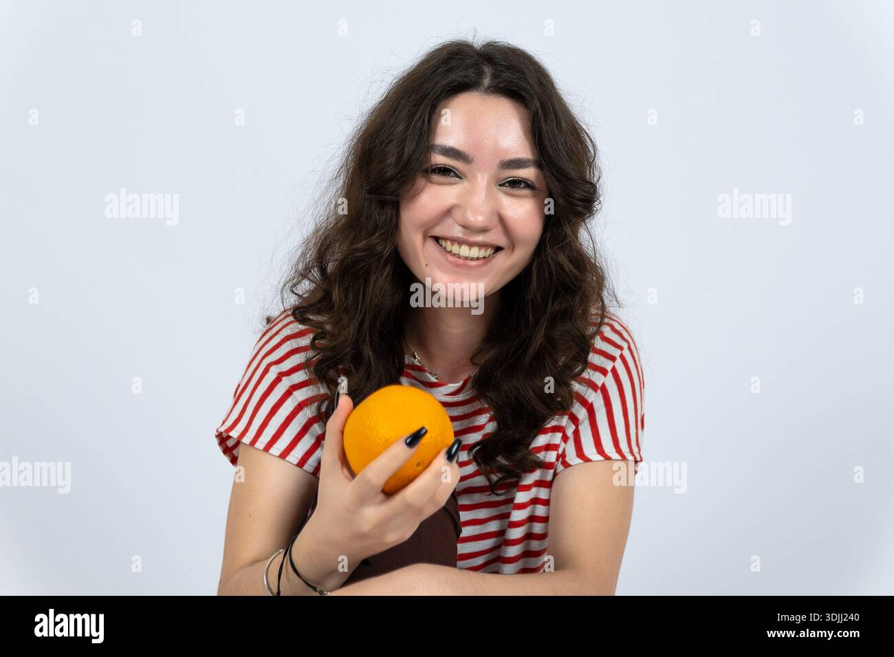Lächelnde Frau, die frisches Orangenobst im Studio genießt Stockfoto