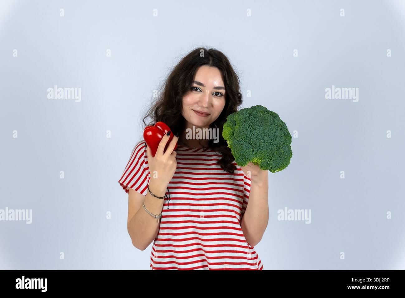 Eine junge Frau mit rotem Pfeffer und grünem Brokkoli Stockfoto