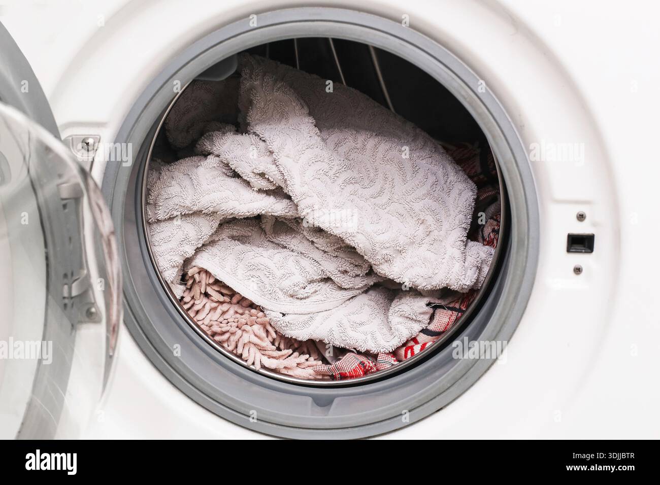 Waschtücher und Reinigungstücher in der Waschmaschinentrommel. Haushaltswäsche. Textilhygiene und Hausreinigung. Stockfoto