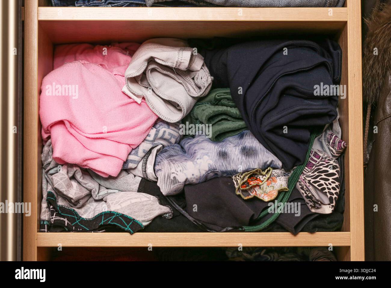 Gefaltete Kleidung in der Schublade. Garderobenaufbewahrung und Konzept der Heimorganisation. Alltagsbekleidung ordentlich angeordnet. Häuslicher Lebensstil. Stockfoto