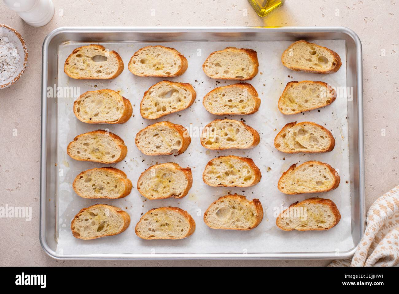 Gebratene Baguetteschnitten auf einem Backblech mit Olivenöl, Salz und Pfeffer zu Crostini oder Bruschetta Stockfoto