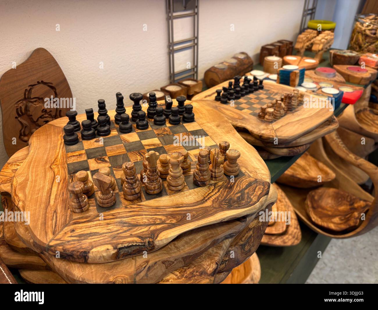 Schachset aus Olivenholz / Schachbrett mit Stücken. Griechische Handwerkskunst, Souvenirs und Schüsseln stapeln sich in einem Laden in Athen, Griechenland. Stockfoto