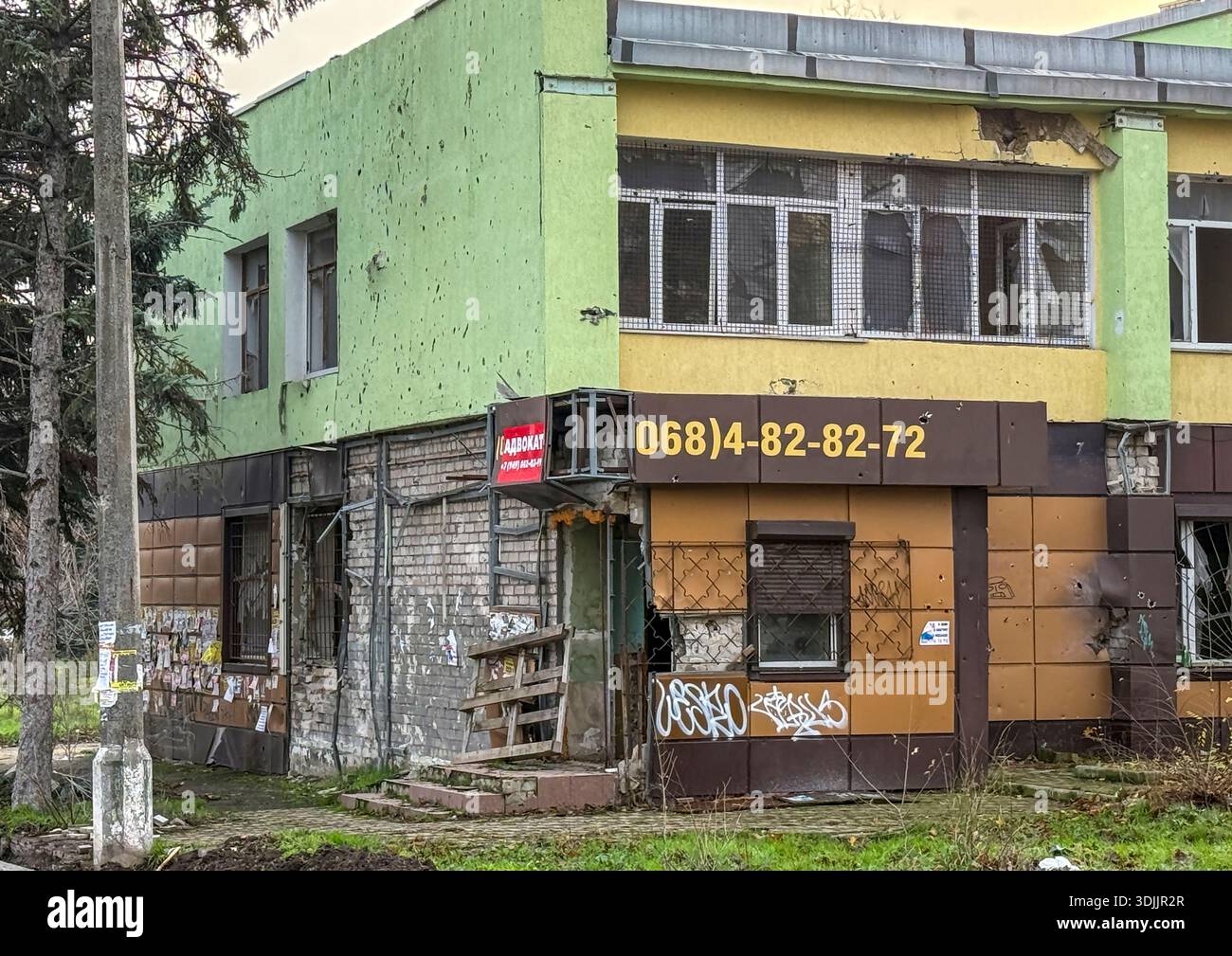 Beschädigtes zweistöckiges Geschäftsgebäude mit zersplitterten Fenstern, Oblast Donezk, Mariupol, Ukraine Stockfoto