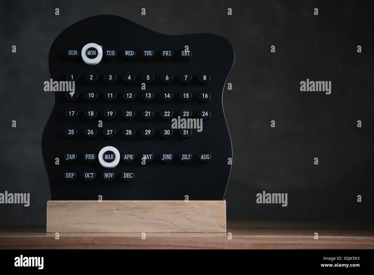 Minimalistischer schwarzer Kalender auf Holzständer mit hervorgehobenen Montagen und Monat März Stockfoto