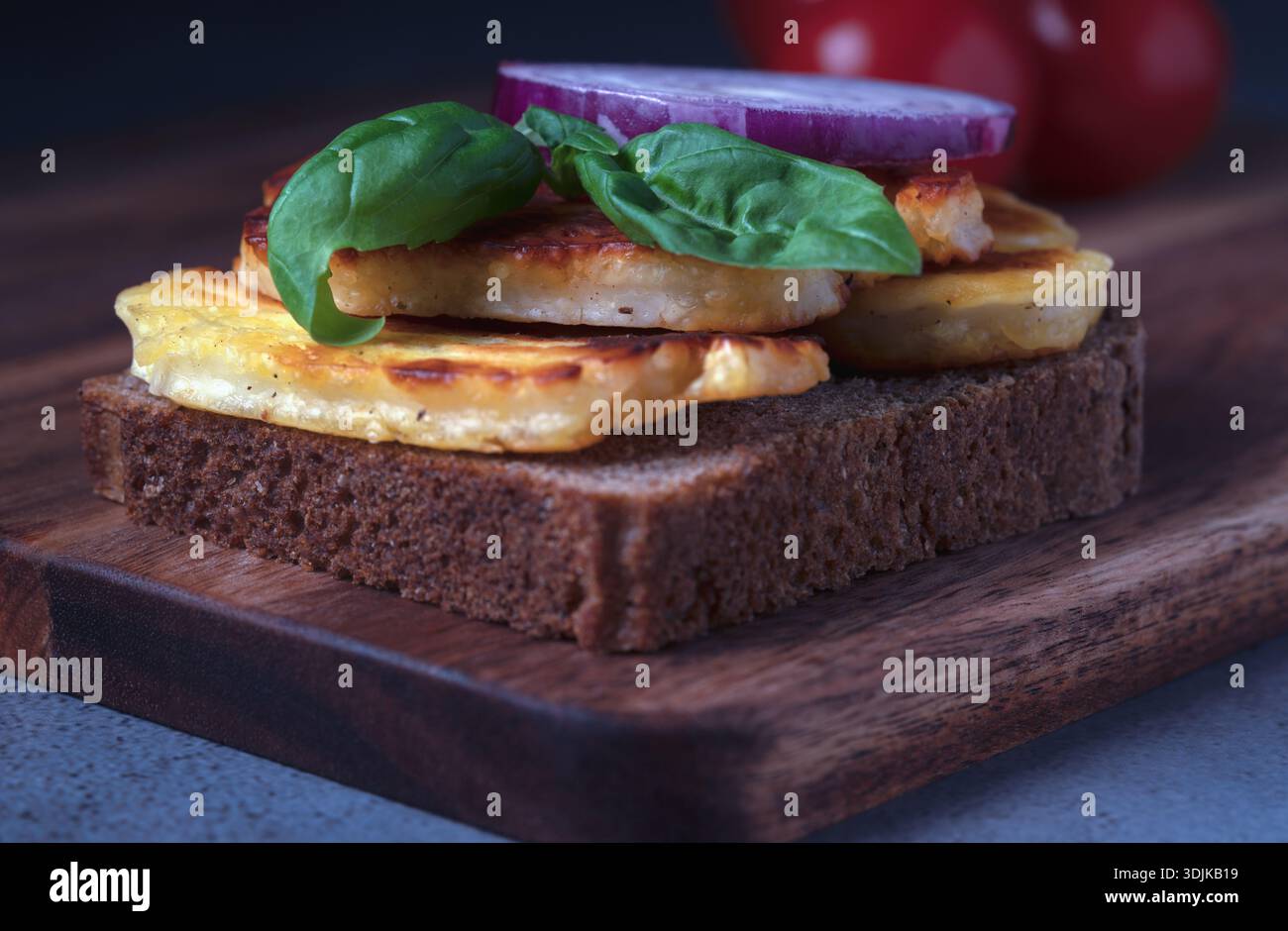 Gesunder Snack mit goldgegrilltem halloumi-Käse und aromatischem Basilikum auf einer Scheibe dunklem Roggenbrot Stockfoto