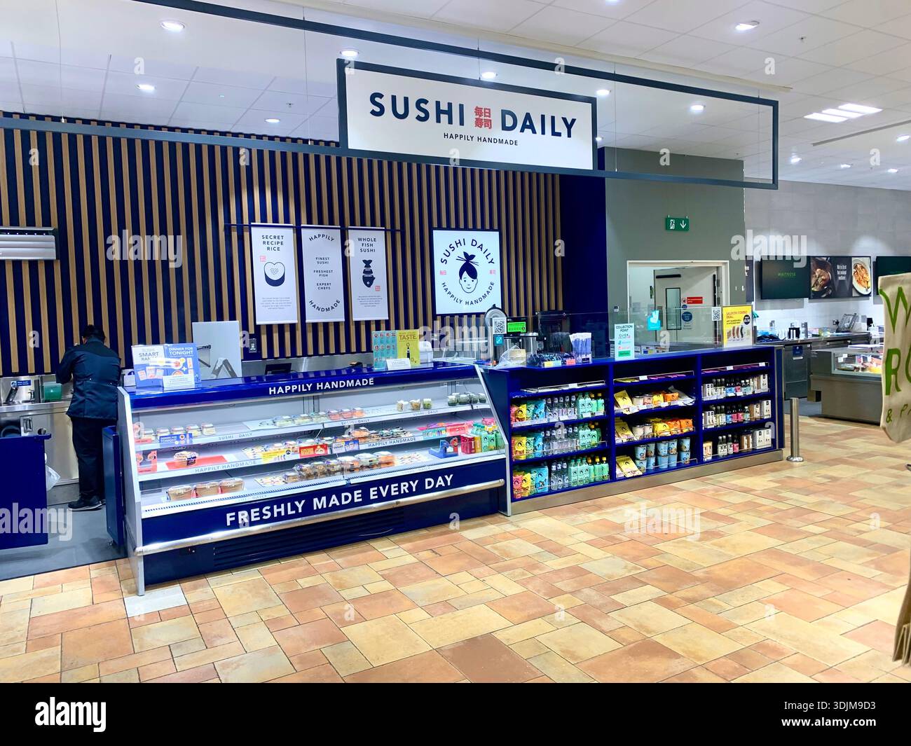 Täglich Sushi-Theke in einem Supermarkt mit frisch zubereitetem Sushi in einem gekühlten Schrank und einem Mitarbeiter, der hinter dem Theken arbeitet Stockfoto