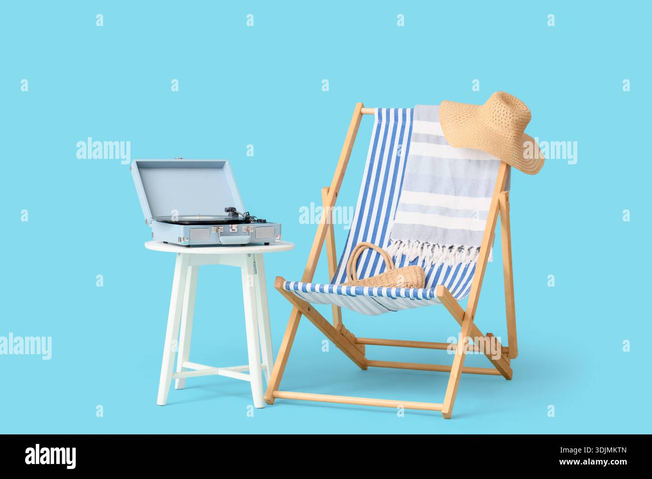 Schallplattenspieler auf Tisch mit Liegestuhl und Strandaccessoires vor blauem Hintergrund Stockfoto
