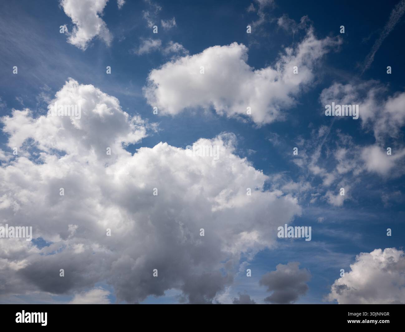 Helle weiße Cumulus-Wolken an einem tiefblauen Sommerhimmel, schöne Wetterkulisse tagsüber. Stockfoto
