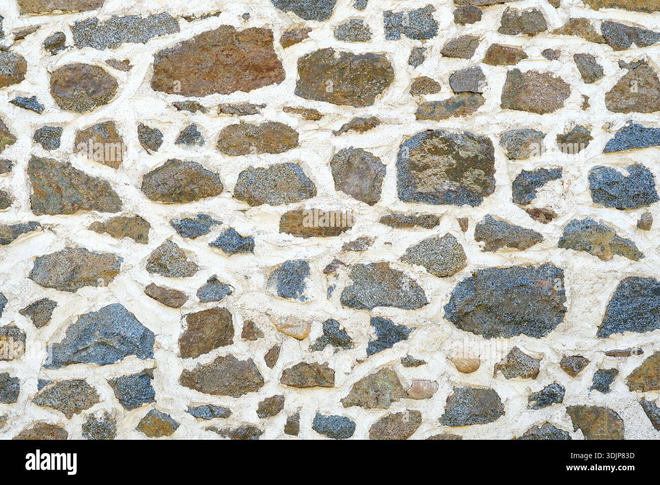 Hintergrund einer Mauermauer aus Naturstein oder Sandstein mit Zement in Südfrankreich. Detaillierte Steinstruktur in Beige, Braun, Grau und Blau Stockfoto