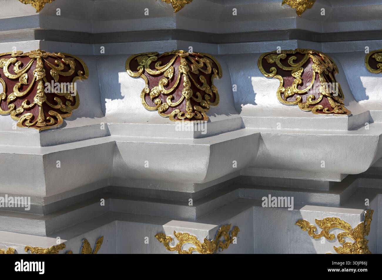 Majestätische Golddekoration an der weißen Tempelwand. Dieses komplizierte traditionelle thailändische Ornament zeigt ein wunderschönes Muster, klassisches und heiteres Detail der Antike Stockfoto