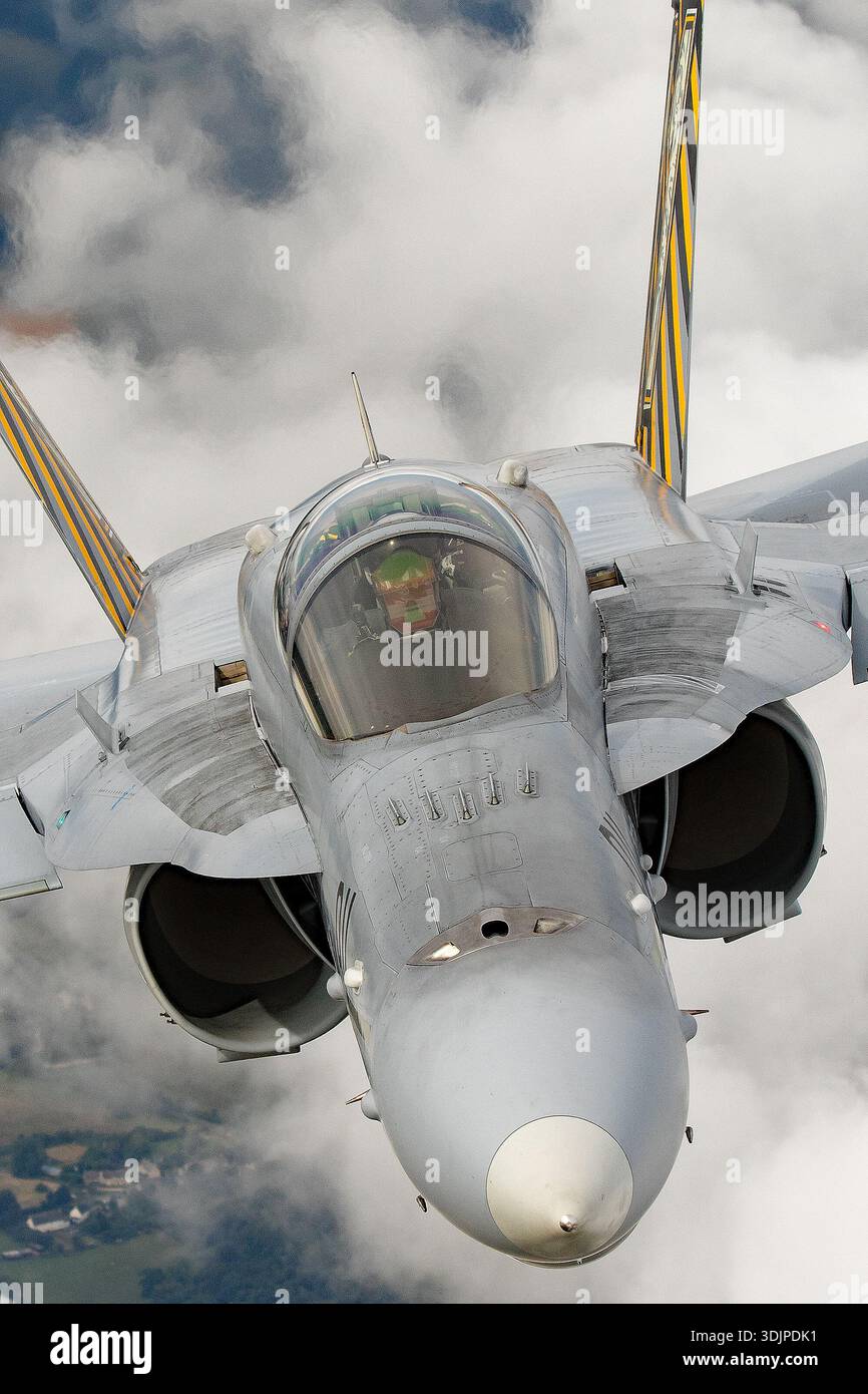 Das Bild zeigt eine F/A-18C Hornet der Schweizer Luftwaffe, die sich während des Fluges frontal nähert. Dieses zweimotorige Kampfflugzeug verwendet Nachverbrennungs-Turbofan-Motoren von General Electric F404 und dient als Luftabwehr- und Luftabwehrfunktion. Deutlich sichtbar sind die Cockpit-Haube, der vordere Rumpf, die Flügelwurzeln und die markante Tigerfarbe mit Staffelmarkierungen während des Royal International Air Tattoo 2019. Stockfoto