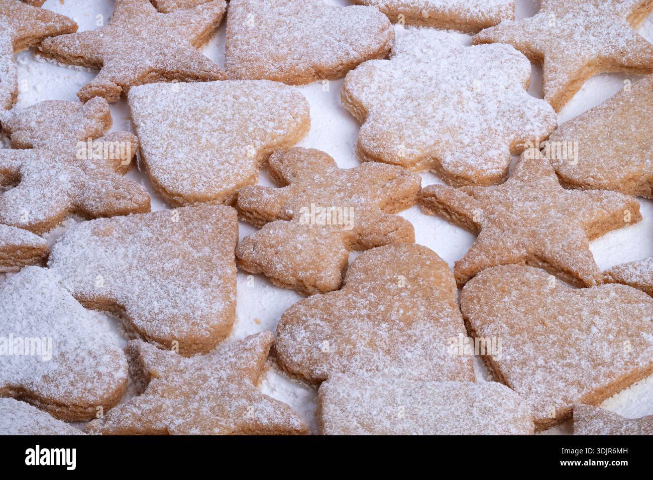 Verstreute handwerkliche Kekse mit Puderzucker, verschiedene Silhouetten mit Herzen und Blumen, rustikale hausgemachte Verarbeitung, natürliches Licht Highli Stockfoto