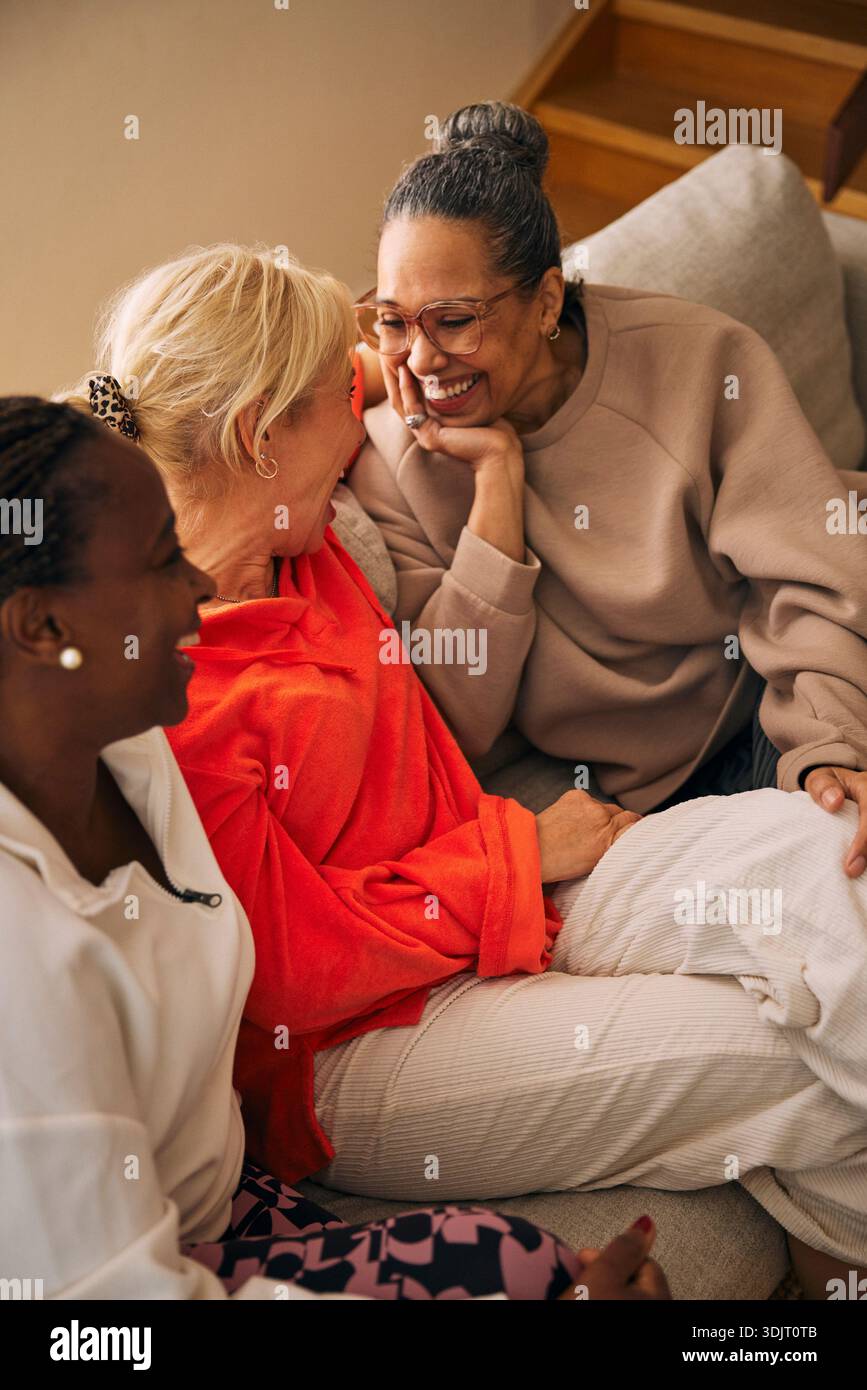 Hochwinkelansicht einer glücklichen, Reifen Frau, die liebevoll eine Freundin ansieht, während sie auf dem Sofa sitzt Stockfoto
