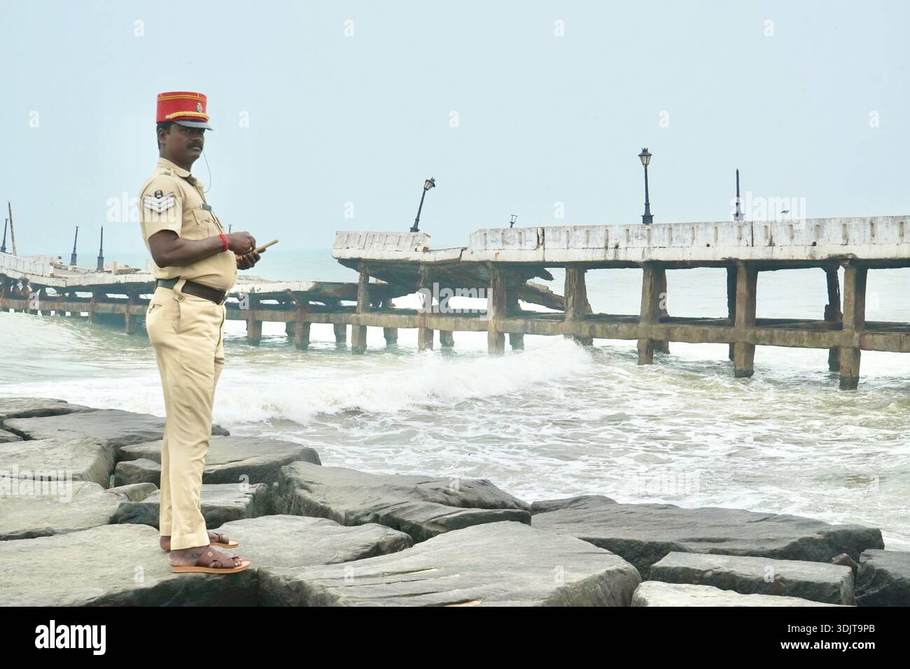 Indischer Polizeibeamter am Rocky Shore am Damaged Pier, Puducherry, Indien Stockfoto