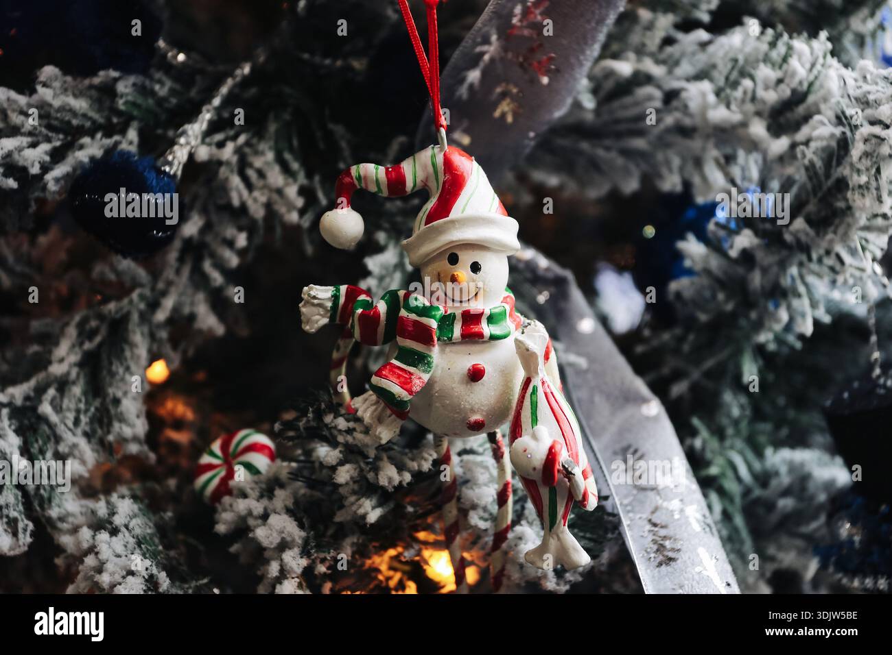 Weihnachtsschmuck mit Schneemännern hängt an verzierten Baumzweigen mit Lichtern und Winterdekorationen. Festliche Feiertagsatmosphäre, traditionelle saisonale Einrichtung. Stockfoto