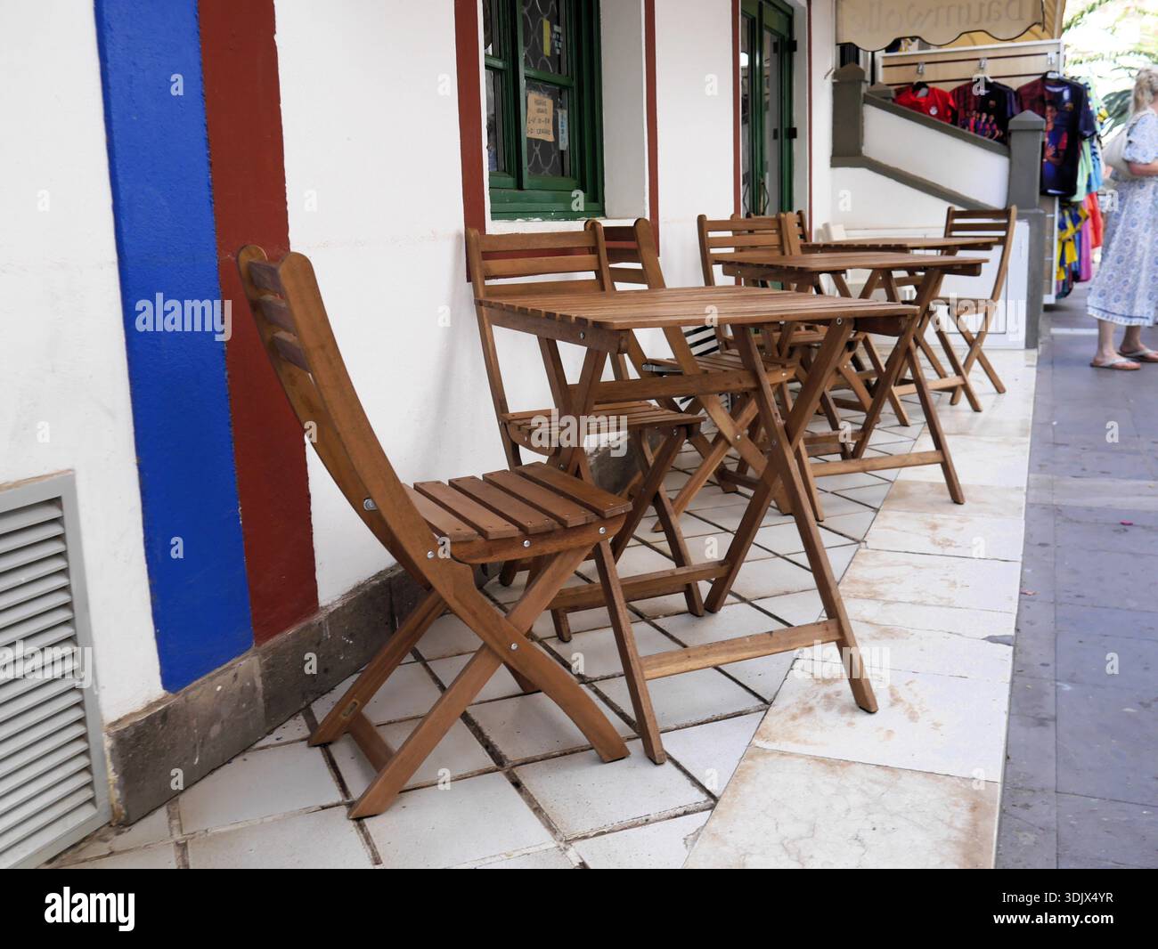 Sklum Delawar Faltbare Akazienholztische und -Stühle vor einem Straßencafé in einer mediterranen Stadt Stockfoto