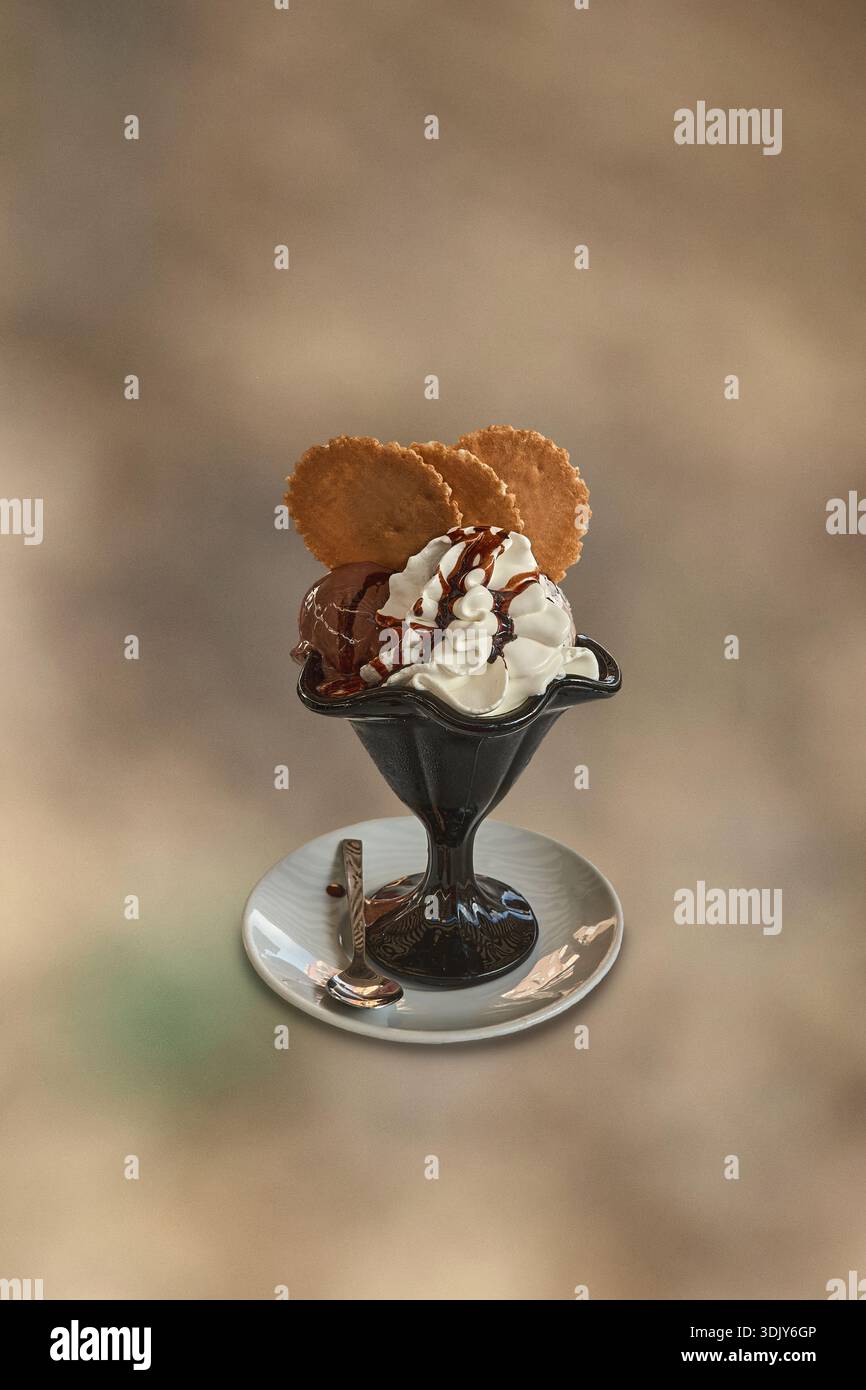 Eisbecher für Gourmet-Schokolade und Vanille mit Schlagsahne und Waffeln in einem schwarzen Glas, minimalistischer Hintergrund mit Kopierraum für Design Stockfoto