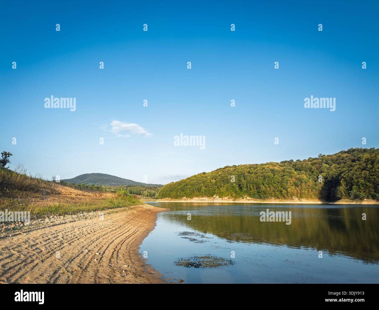 Ruhige Küste des Garasko jezero (Gardasee) in der Nähe von Arandjelovac, Serbien, mit einer Sandbank, Reflexionen auf stillen Wasser und bewaldeten Hügeln, eine malerische d Stockfoto
