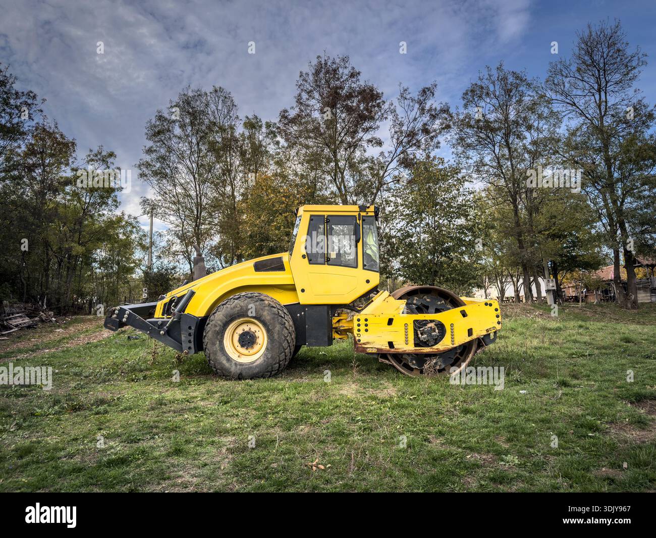 Gelbe Straßenwalze, kleines Modell, auf einer Wiese ausgestellt. Eine Straßenwalze oder Verdichterwalze wird für Asphalt und Straßenrenovierung und -Bau verwendet. Stockfoto