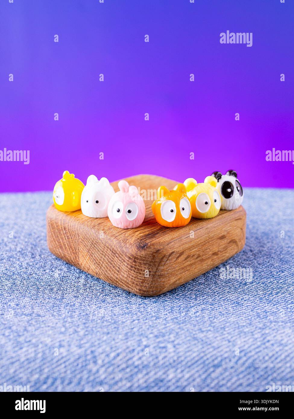 Eine Nahaufnahme einer Reihe von farbenfrohen, bezaubernden Tierfiguren im Kawaii-Stil, die auf einer Holzbühne platziert werden Stockfoto