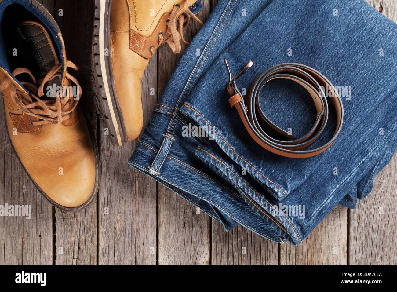Herren Kleidung und Accessoires. Jeans, Schuhe, Gürtel auf hölzernen Hintergrund. Ansicht von oben Stockfoto