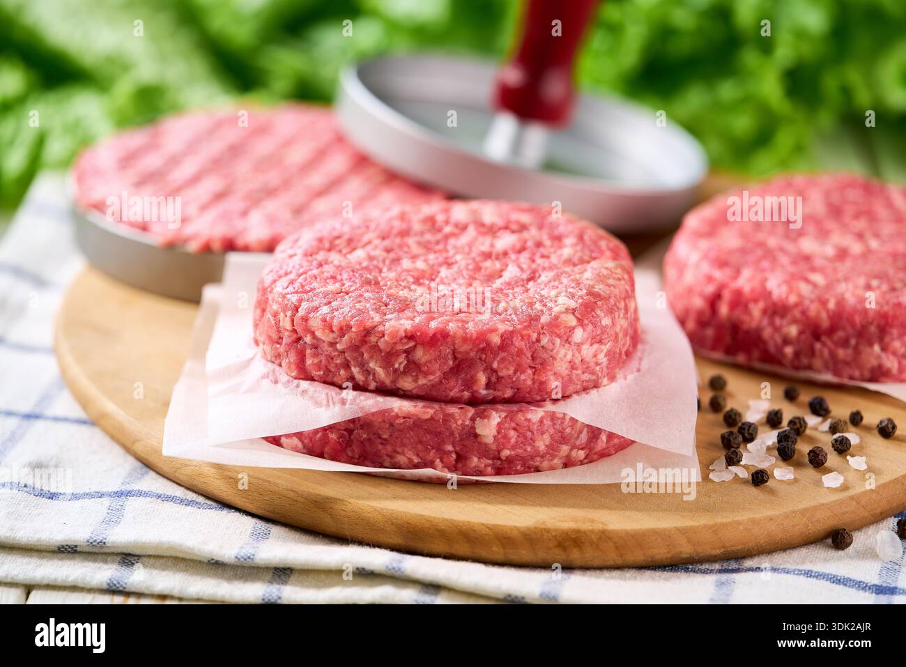 Stapel roher Burger-Rindfleisch-Patties auf einem weißen Tisch, selektiv fokussiert. Natürliches Fleischprodukt. Uniform-Patties kochen in der Burgerpresse. Stockfoto