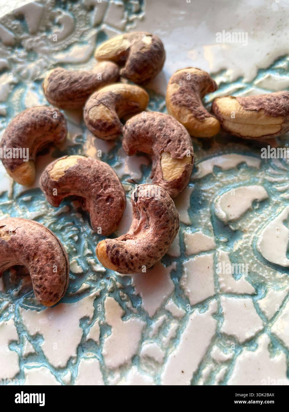 Stillleben einer Platte mit violetten Schalen asiatischen Cashews, 2026, USA - Smartphone-aufgenommenes Stockfoto