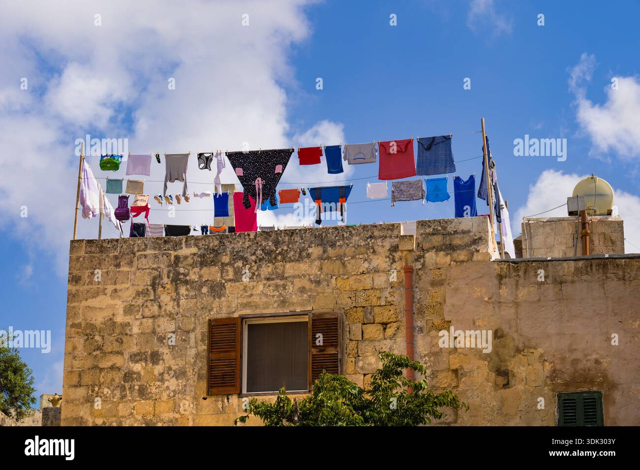 Trocknende Kleidung hängt an Wäscheleinen auf einem Dach eines traditionellen Steinhauses in der Stadt Mdina, Malta. Stockfoto