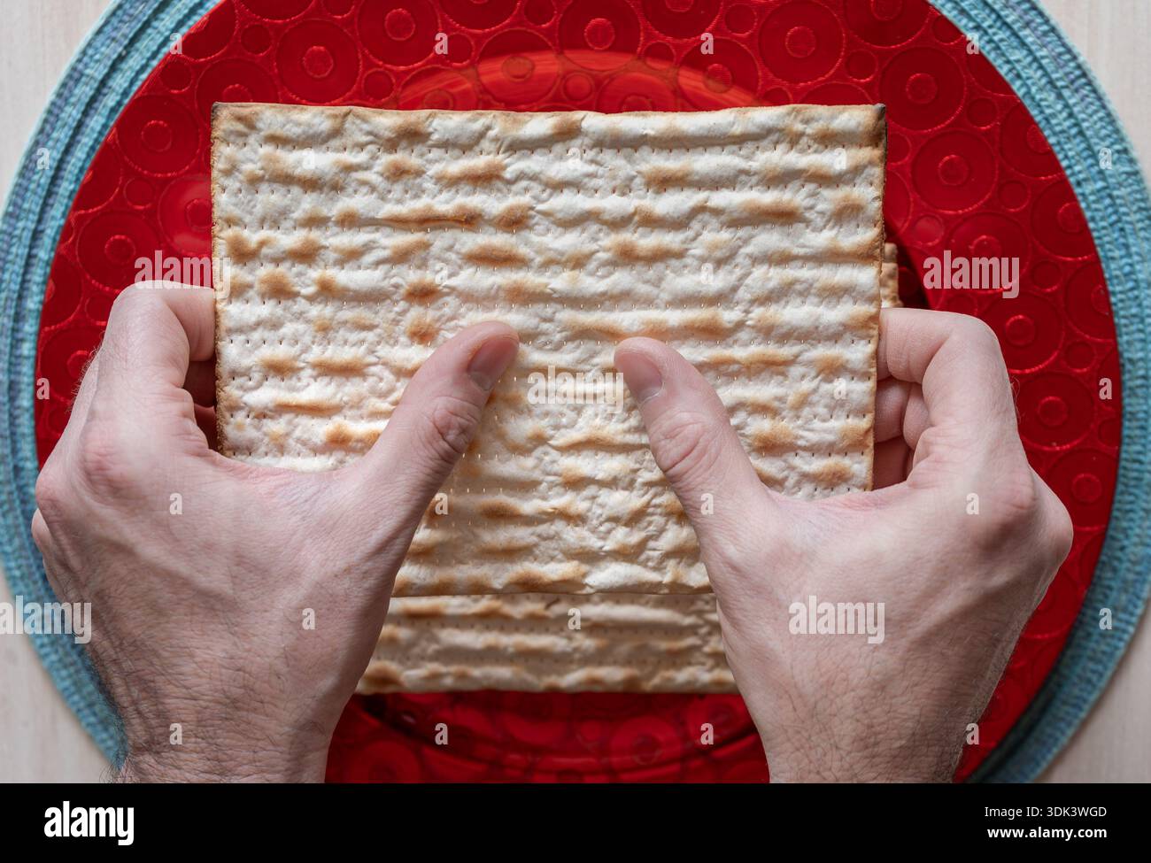 Zwei Hände halten eine Matzah während der jüdischen Pessach-Feier. Stockfoto