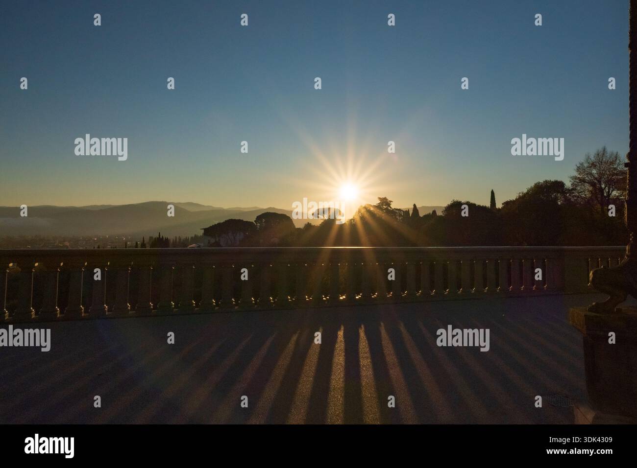 Hinterleuchtung Aufnahme der Sonne bei Sonnenuntergang mit Schatten und Reflexionen über einem Zaun Stockfoto